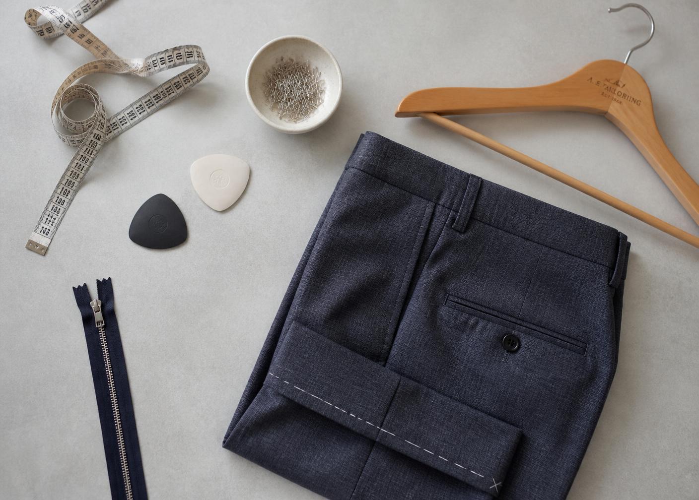 Mesa de trabajo con cinta métrica, cremallera, jaboncillo y un pantalón marcado para el bajo